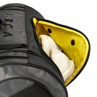 Volt’s grey XL padel bag with the shoe compartment open, ventilated yellow lining, and white sneakers inside.
