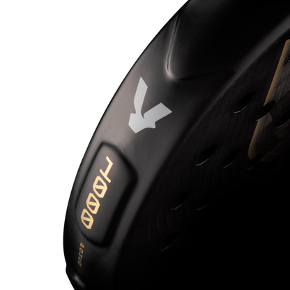 Side detail of the Volt 1000 V5 padel racket, showcasing the classy black and white V logo, the metallic gold 1000 numbers and highlighting the racket shape details on the side.