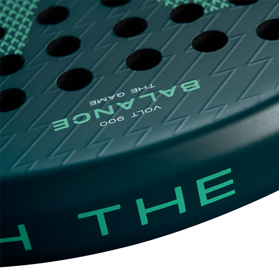 Close-up of the Volt 900 V4 padel racket's face, showcasing the carbon texture and 'Balance The Game' text in green.