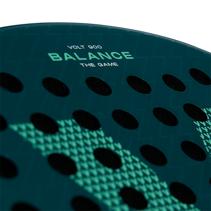Zoomed-in view of the Volt 900 V4 padel racket's face, showcasing the 'Balance The Game' text and perforation pattern.
